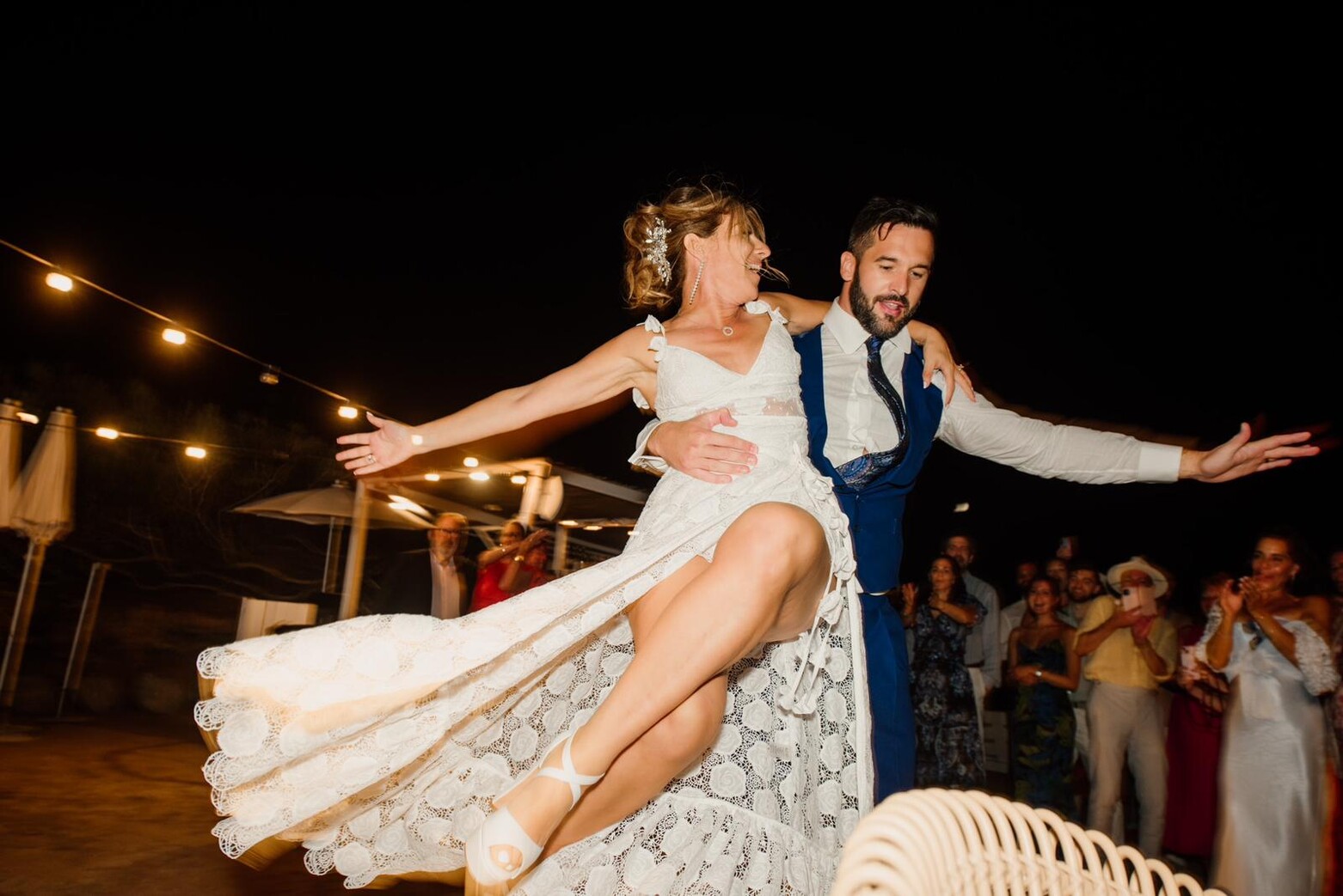 Bride lifted mid-dance under string lights